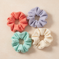 Coral, lilac, mint, sky-blue, and cream hair ties arranged on a warm ivory surface
