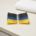 Black, cobalt blue, and sunny yellow sectioning clips arranged on a warm-white salon surface