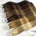 European 12A Virgin Tape-In Hair Extensions in multiple shades from black to blonde fanned out on white surface showing tape tabs