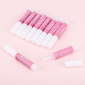 Pink and white nail glue tubes arranged on a soft pink background